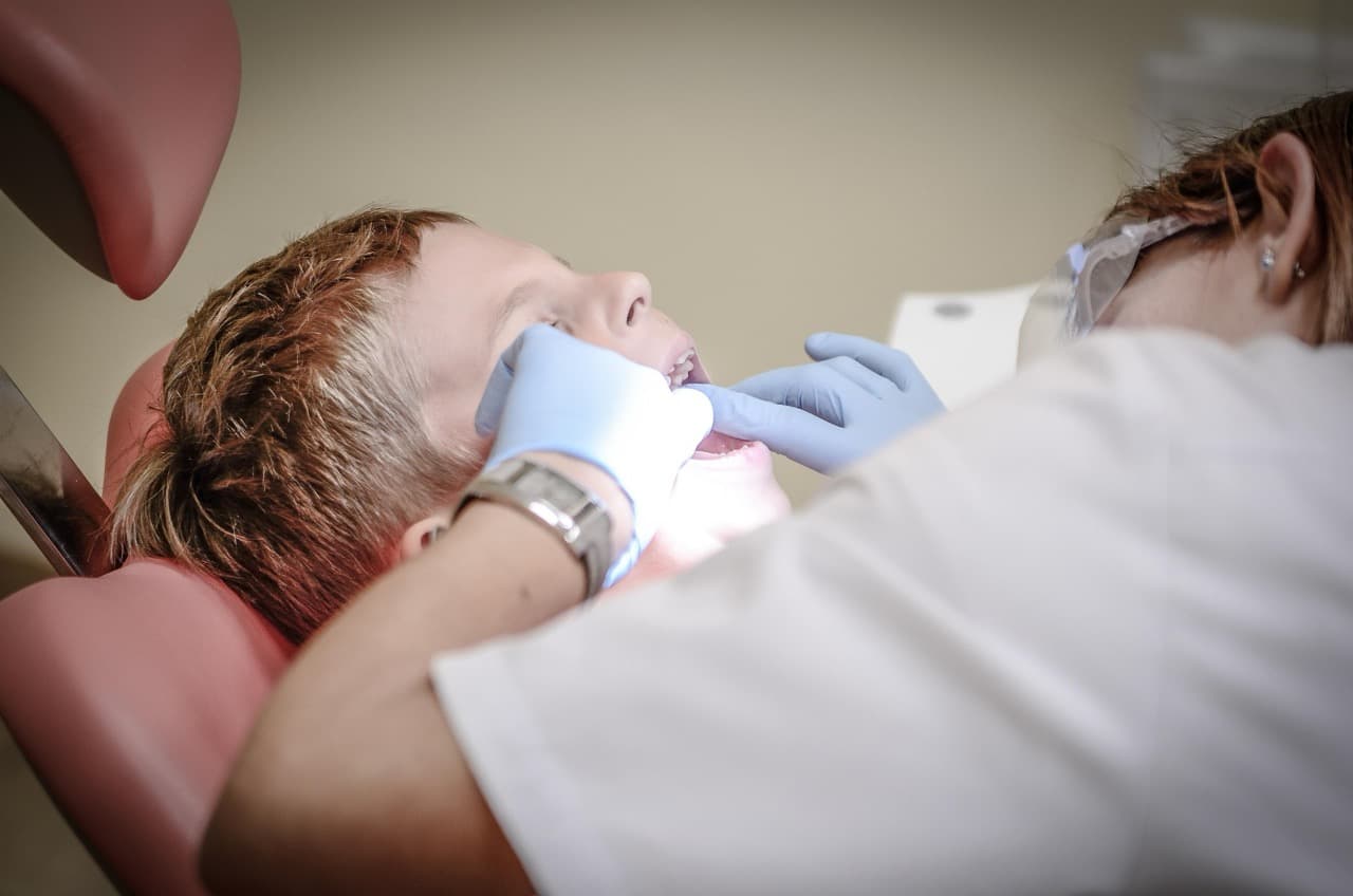 Young child getting a dental exam with a dentist examining their mouth