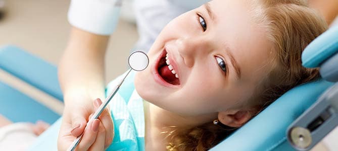 Smiling little girl in dental chair with dentist
