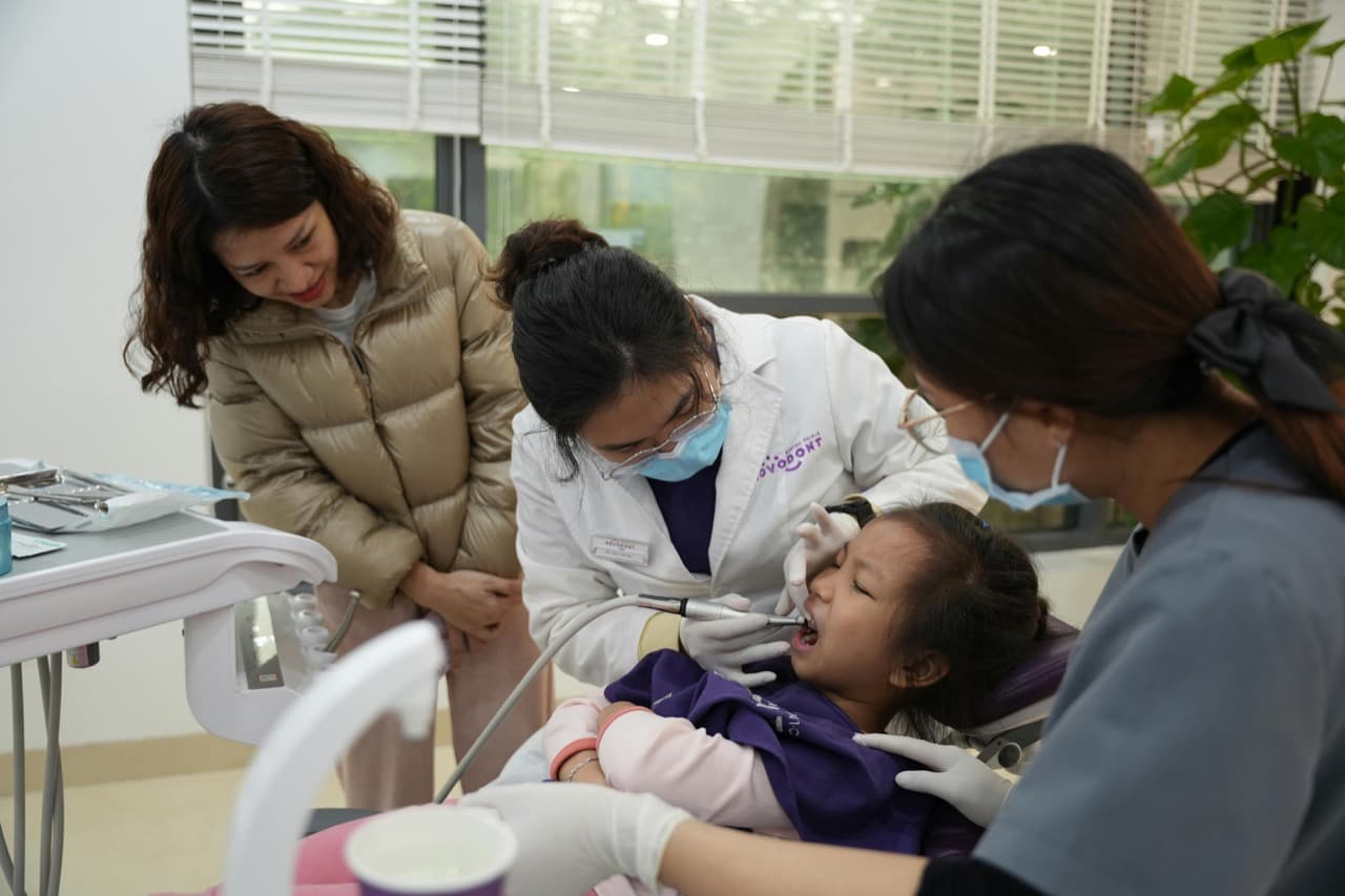 Young child getting a dental exam while parent watches nearby