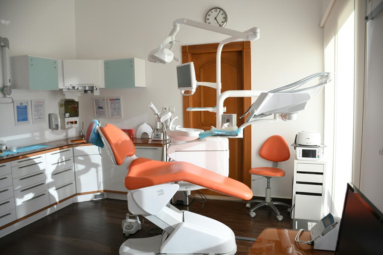 Modern dental treatment room with dental chair, overhead light, and equipment