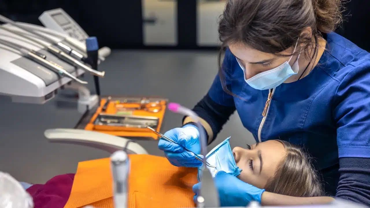 Female dental hygienist performing a deep cleaning on a patient with dental instruments visible