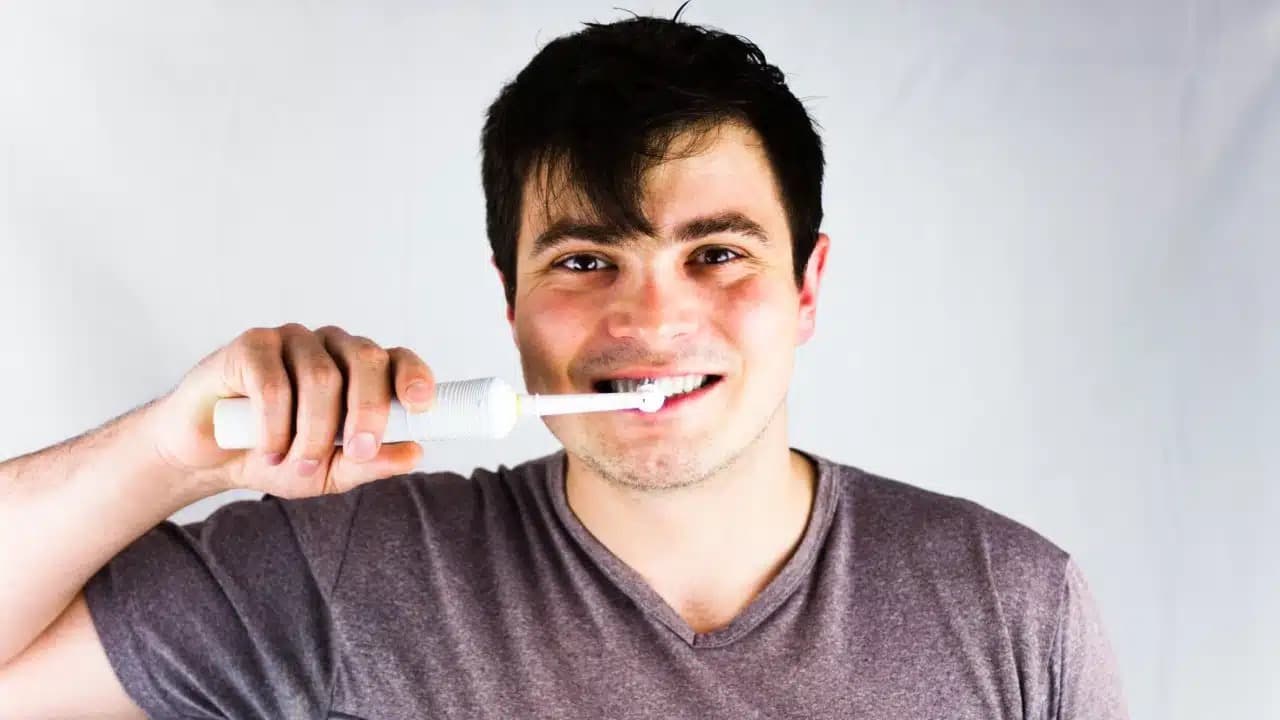 Woman smiling while brushing teeth, illustrating daily oral hygiene routine